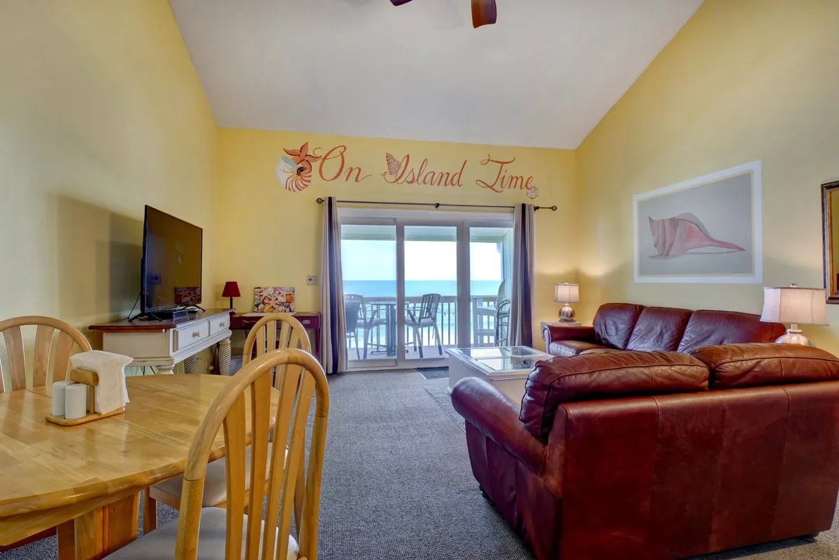 A cozy, inviting space with a large window framing ocean views. The sofa, dining table, and ample natural light create a warm setting for family meals, conversations, or simply enjoying the serenity of the coast.