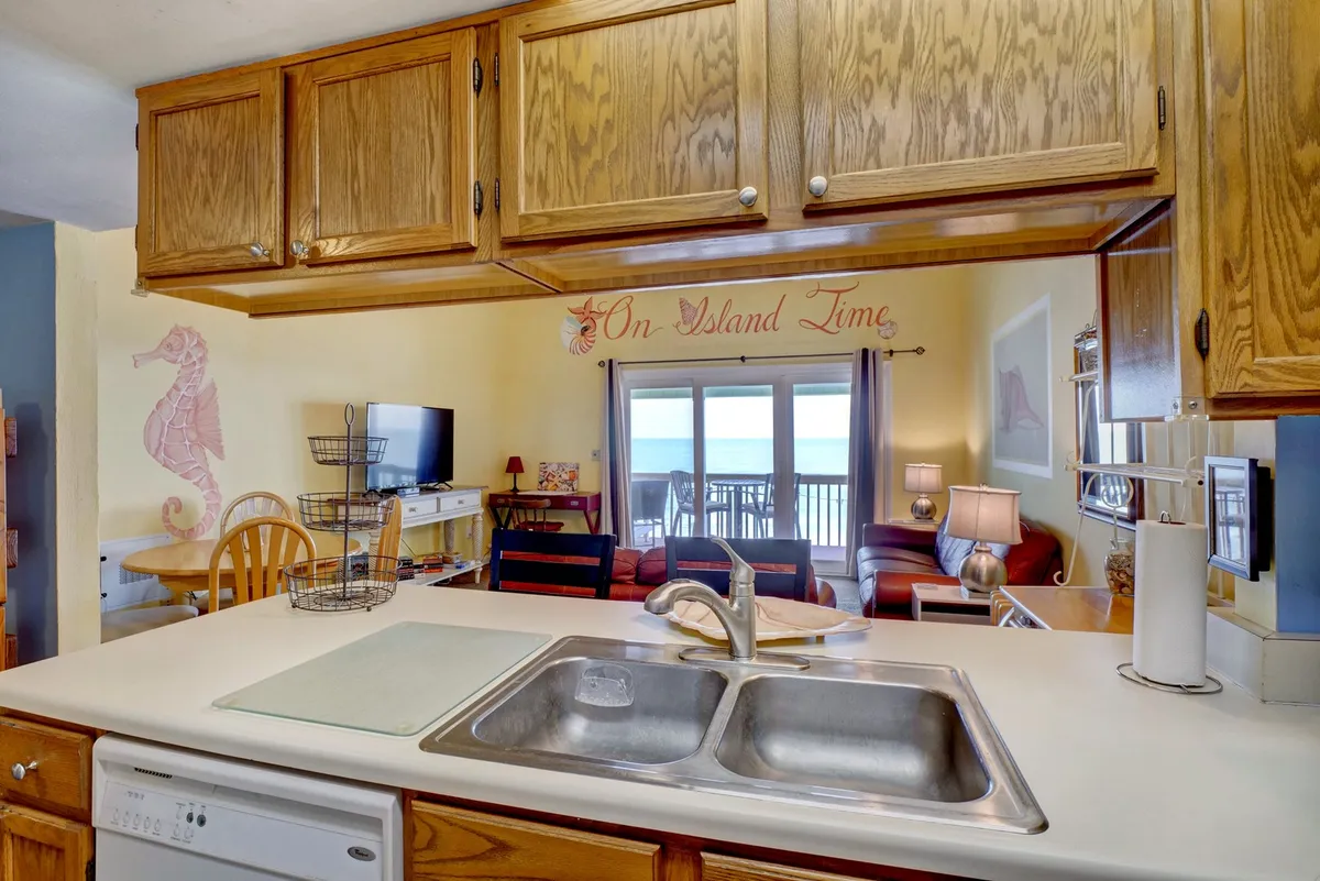 A bright open-plan kitchen and seating area with large windows providing glimpses of the outdoors. The space is inviting, perfect for preparing meals together, entertaining, or simply relaxing with a view.