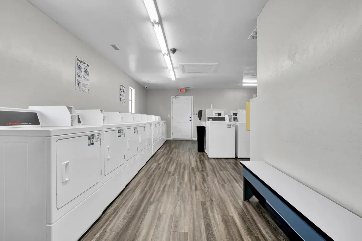 A practical, well-maintained laundry facility with a row of washing machines and benches for waiting or socializing. The space feels clean and organized, with a welcoming community feel as guests tend to their laundry.