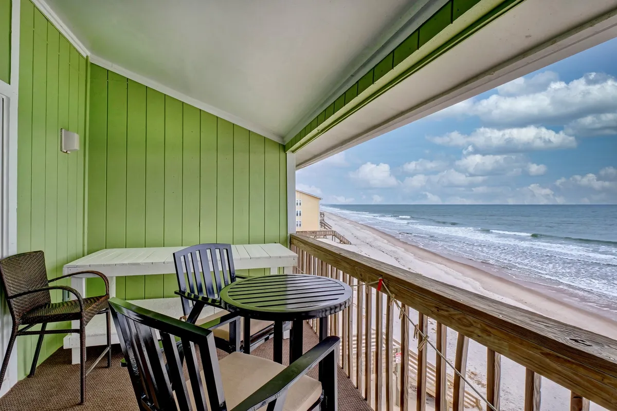 This image features a tranquil exterior view of the condo's private deck, complete with comfortable outdoor seating and a stunning panoramic ocean view. The scene hints at the perfect spot for sunset drinks, al fresco dining, or simply relaxing while gazing at the water.