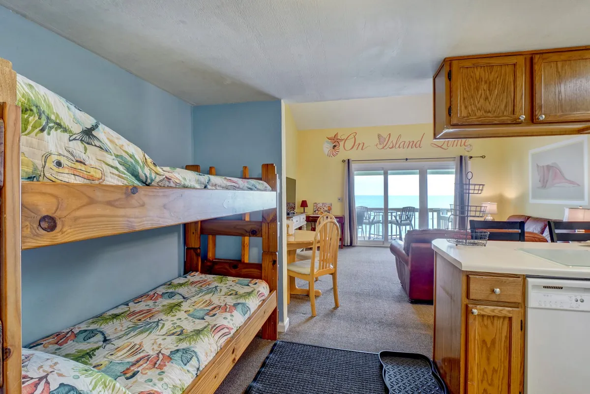 An inviting interior scene showing a dining area with a view of the outdoors and cozy bunk beds nearby. The space radiates a light-hearted, communal atmosphere, perfect for group gatherings, shared meals, and affordable group travel.